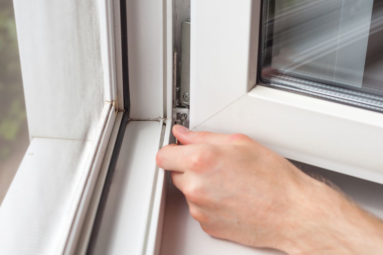 Hand, die an der Dichtung eines geöffneten Fensters zieht